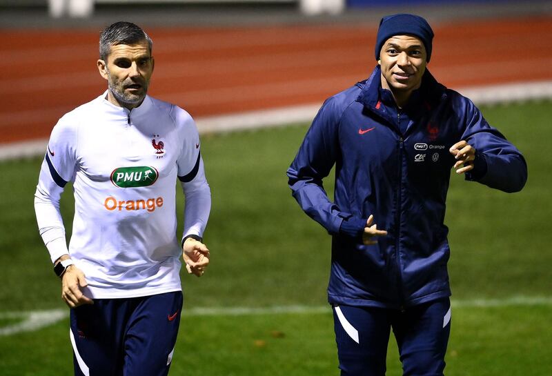 Kylian Mbappe, right, alongside a member of the France coaching team. AFP