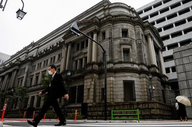 A man wearing a protective mask walks past the headquarters of the Bank of Japan. The Japanese central bank has refused traders' request to work from home despite a rise in Covid-19 cases in Tokyo. Reuters.