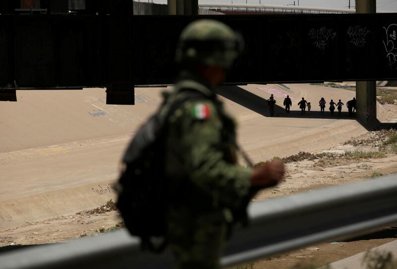 A member of Mexico's National Guard looks at people walking in El Paso, US, after illegally crossing the border. Reuters