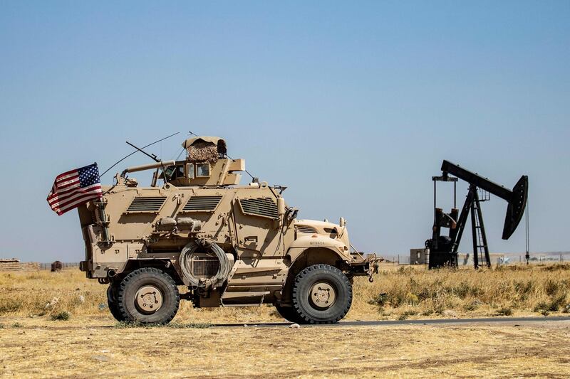 A US military vehicle passes a pumpjack in the Rumaylan oil field in north-east Syria. The major oil field, located near a US airbase, has been among the Syrian Kurds' most prized assets since regime forces withdrew early on in the Syrian civil war. AFP