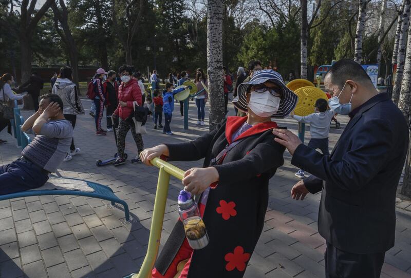 A Chinese woman wears a protective mask as she exercises on equipment at Ritan Park in Beijing, China. Getty Images