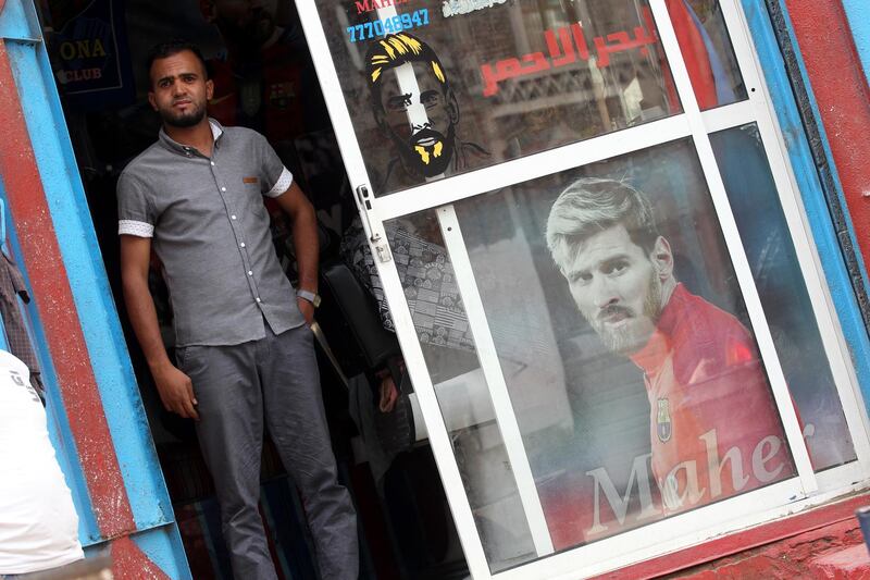 A barber waits for customers inside a shop decorated with posters of Argentine footballer Lionel Messi, in Sana'a, Yemen. EPA