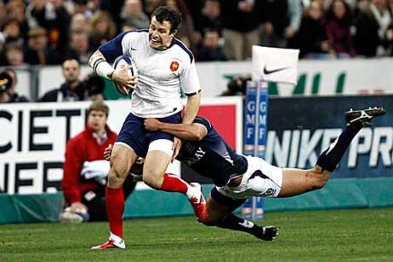 France's Damien Traille, left, avoids the tackle of a Scotland player.