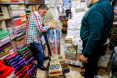 Palestinian craftsman Issam Zughair (L) moves a large Ramadan lantern in his shop in the old city of Jerusalem on May 2, 2019. In his shop in Jerusalem's Old City, Zughair makes traditional lanterns for Muslims marking the holy month of Ramadan, battling competition from cheap Chinese imports. The shop boasts a mix of large and small lamps on show, some hanging from the ceiling while others are displayed outside to draw the attention of passers-by during the lively Ramadan evenings. / AFP / AHMAD GHARABLI
