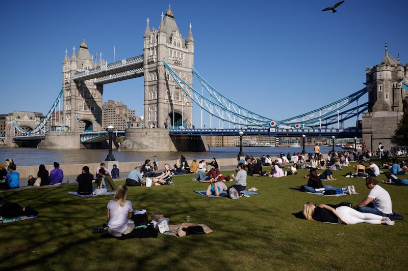 People relax in the sunshine on the south bank of the River Thames, near Tower Bridge, London. The UK recorded its warmest March day in 53 years on Tuesday. Bloomberg