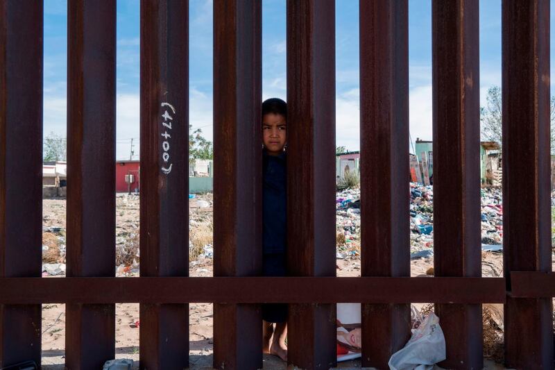 A young Mexican boy is pictured peering from the Mexican side of the Border Fence in Anapra, near El Paso, Texas. Paul Ratje / AFP