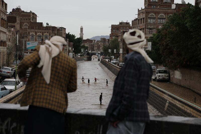 People watch boys playing in floodwater in the old quarter of Sanaa, Yemen. Reuters