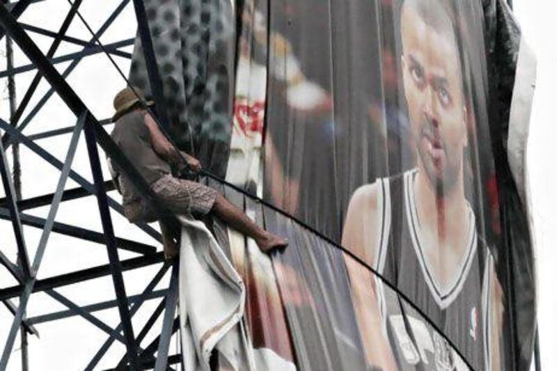 A Filipino worker folds a billboard ad that shows Antonio Spurs Tony Parker as people brace for Typhoon Utor in Manila.