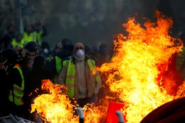 Protesters wearing yellow vests are seen behind a fire as they attend a demonstration of the 'yellow vests' movement in Angers, France. Reuters
