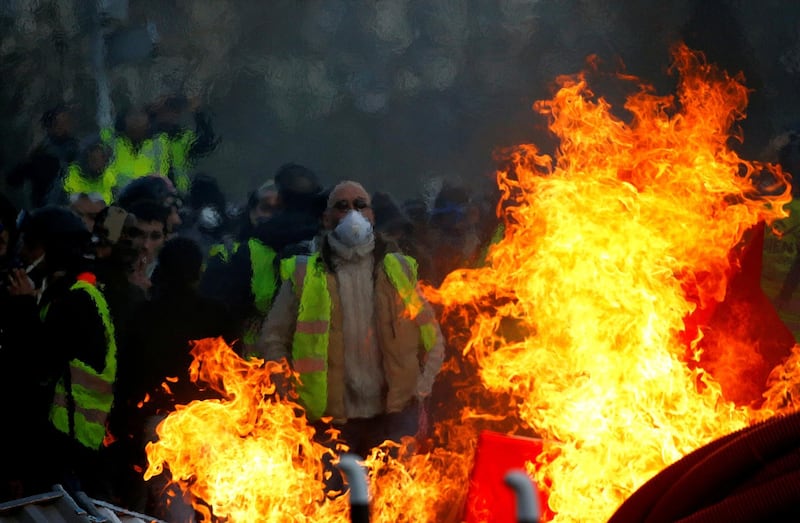 FILE PHOTO: Protesters wearing yellow vests are seen behind a fire as they attend a demonstration of the "yellow vests" movement in Angers, France, January 19, 2019. REUTERS/Stephane Mahe/File Photo