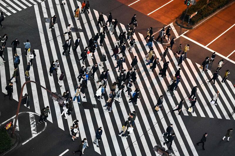 Pedestrians cross a street in Tokyo's Shinjuku area as the city reported 418 daily new coronavirus infections.  AFP