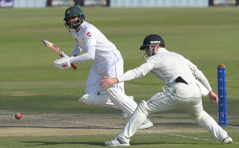 Pakistani batsman Azhar Ali (L) plays a shot as New Zealand cricketer Henry Nicholls looks on during the second day of the third and final Test cricket match between Pakistan and New Zealand at the Sheikh Zayed International Cricket Stadium in Abu Dhabi on December 4, 2018. / AFP / AAMIR QURESHI
