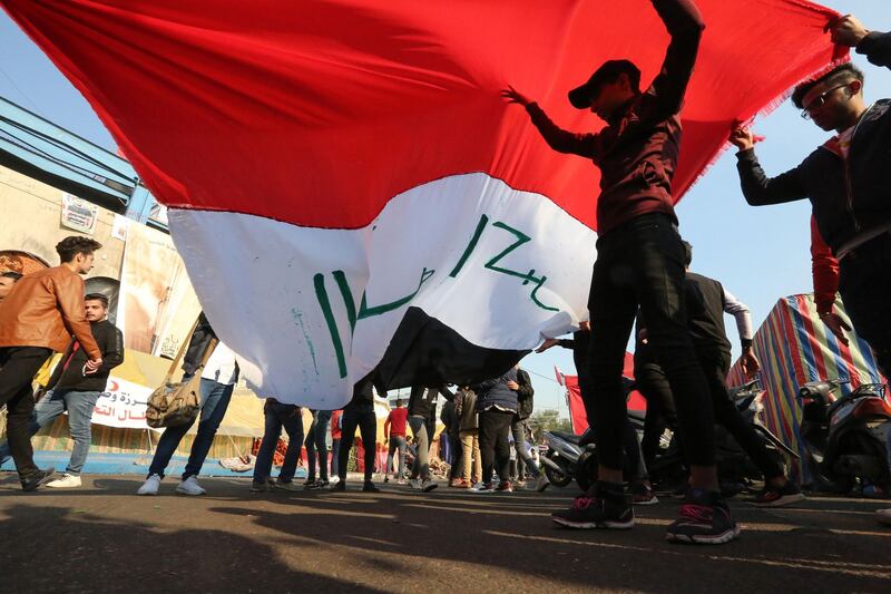 Iraqi anti-government protesters carry a large natioanl flag during ongoing demonstrations in the capital Baghdad's Tahrir square.  AFP