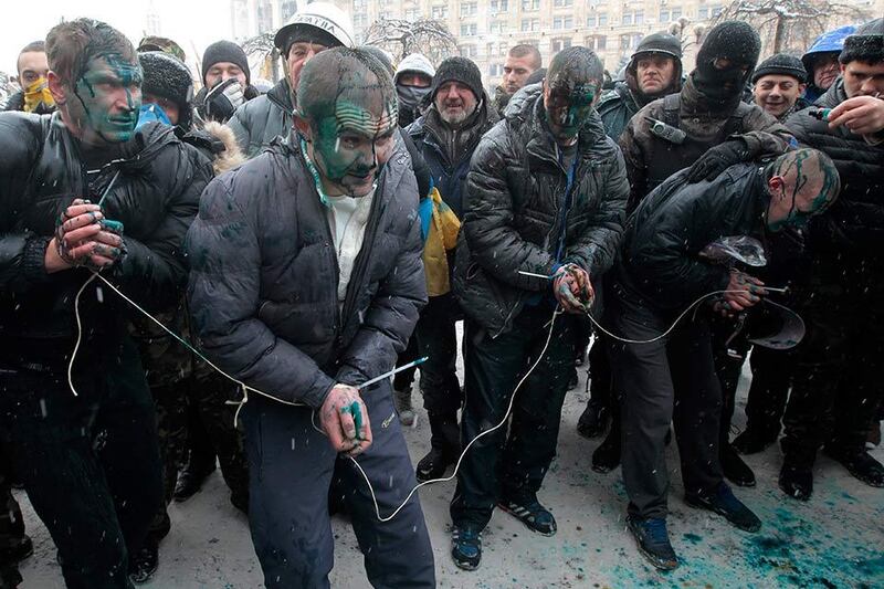 Pro-government hired thugs, referred to as "titushki" are captured by protesters in central Kiev, Ukraine, Wednesday, Jan. 22, 2014. Anti-government protesters tied  the suspected hired thugs, stained them with paint and then released them.  Police in Ukraine's capital on Wednesday tore down protester barricades and chased demonstrators away from the site of violent clashes. (AP Photo/Sergei Chuzavkov)