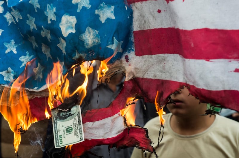 Protesters burn an American flag and a U.S. one-hundred dollar bill during a demonstration on the anniversary of the U.S. embassy seizure, in Tehran, Iran, on Sunday, Nov. 4, 2018. Iran’s Supreme Leader Ayatollah Khamenei said U.S. President Donald Trump’s policies are opposed by most governments and fresh sanctions on the Islamic Republic only serve to make it more productive and self-sufficient, the semi-official Iranian Students’ News Agency reported. Photographer: Ali Mohammadi/Bloomberg