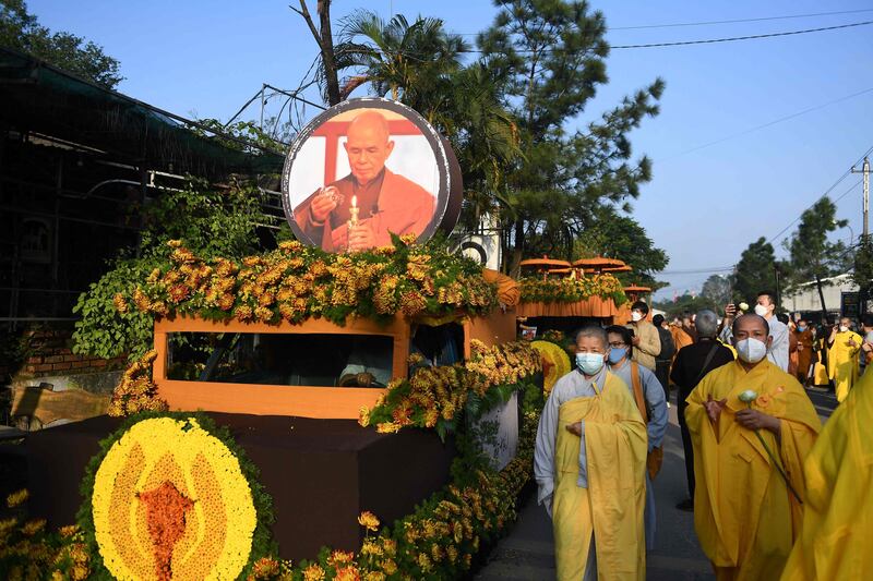 Buddhist followers walk by the convoy carrying the coffin of Thich Nhat Hanh. AFP