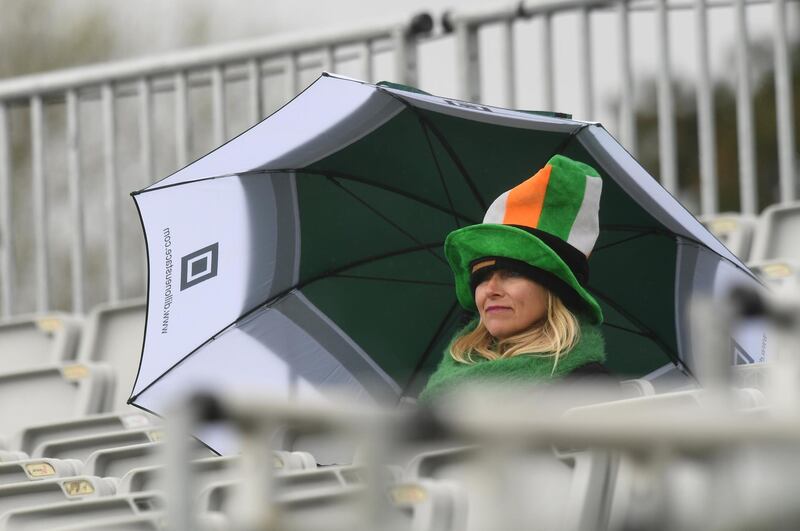 A fan shelters from the rain at Malahide on Friday. Clodagh Kilcoyne / Reuters