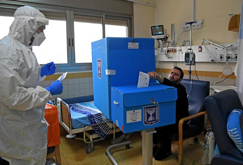 An Israeli electoral worker dressed in a full protective gear waits as a Covid-19 patient casts his ballot at the Sheba Medical Centre in Ramat Gan near Tel Aviv. AFP