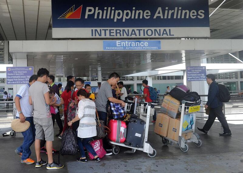 Passengers enter the Philippine Airlines passenger terminal at Manila airport on August 11, 2015.  The carrier's parent company, PAL Holdings, reported its first-half net profit soared nearly ten-fold to 127 million USD, boosted by strong demand during the peak summer months.   AFP PHOTO / Jay DIRECTO


