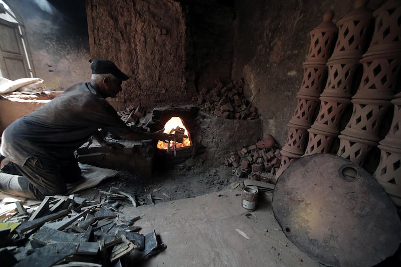 An Egyptian worker puts the wood inside a traditional oven at a pottery workshop in Old Cairo, Egypt.