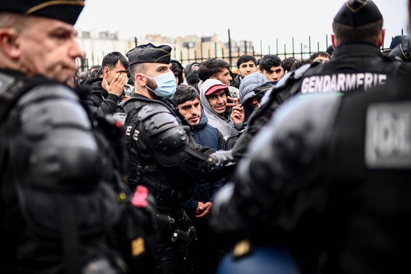 French gendarmes escort migrants queuing to board buses for temporary shelter during the evacuation of their makeshift camp that housed hundreds, mostly Afghan, in Paris. AFP