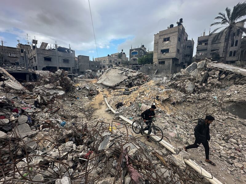 Palestinians walk among the rubble, as they inspect houses destroyed in Israeli strikes. Reuters