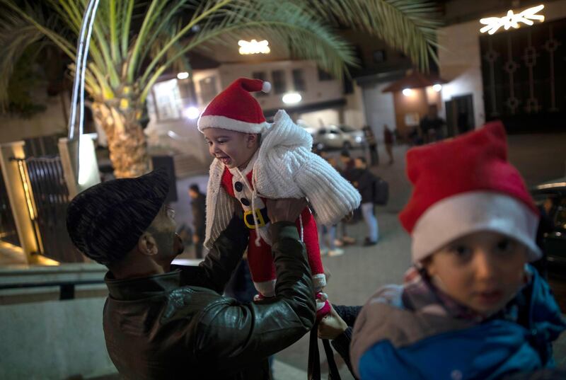 A Palestinian Christian man plays with his baby as they wait for the Christmas Mass outside the Holy Family Catholic Church in Gaza City. AP Photo