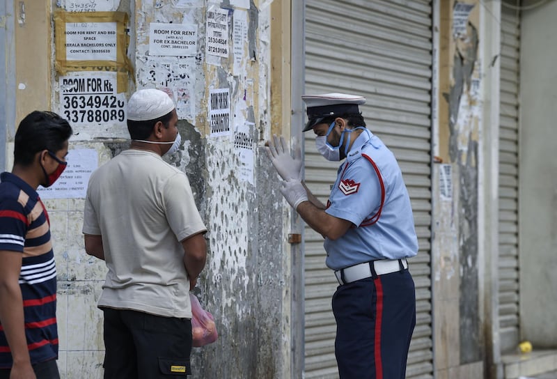 A Bahraini police officer instructs foreign workers on proper self-protection measures amid the Covid-19 pandemic in the old marketplace of the capital Manama. AFP