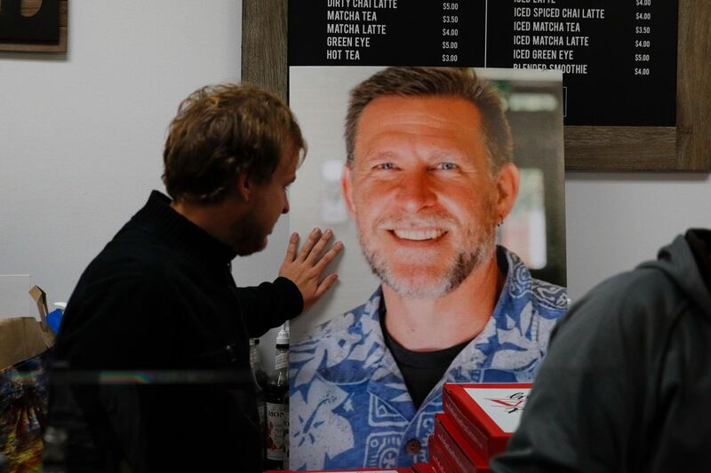 Jordan Hopkins places his hand on the photo of Sean Adler during a vigil at the Rivalry Roasters coffee shop. AP Photo
