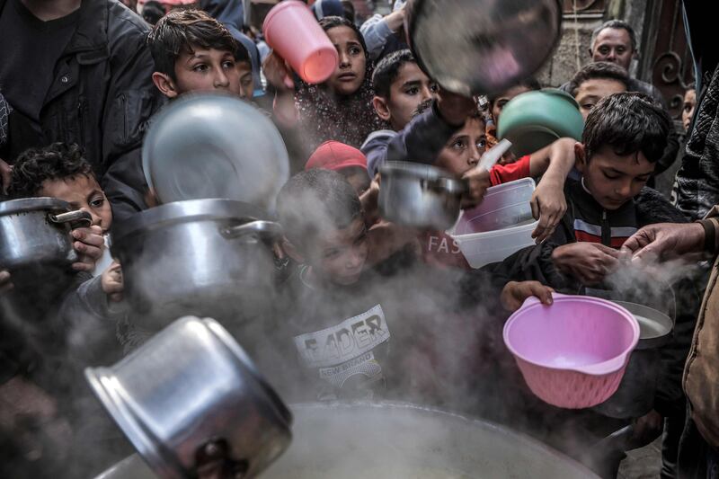 Youths hold out their pots and containers to receive soup on the second day of Ramadan in Gaza city. AFP