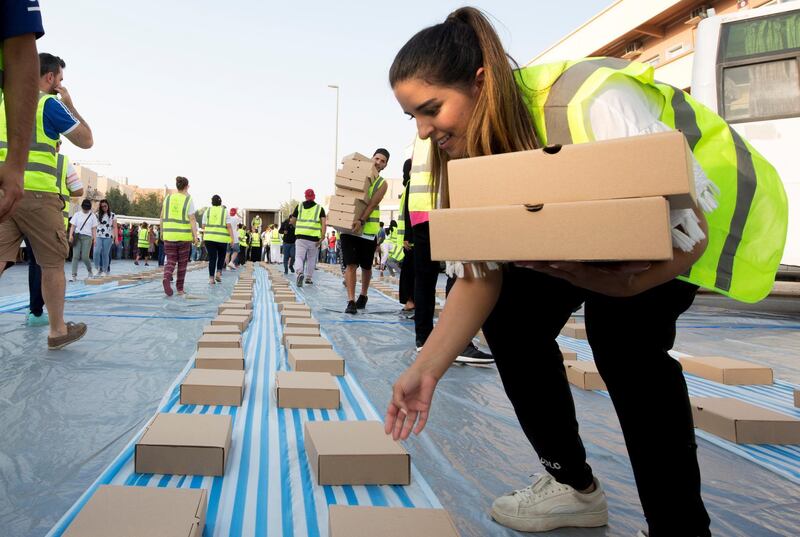 DUBAI, UNITED ARAB EMIRATES -  Volunteers with iftar meal boxes arrange them where the workers will be seated to break their fast.  Dubai Police join hands with Berkeley Assets to serve up Iftar dinner to mark Laylatul Qadr for 10,000 labourers with seating for 5,000 and another 5,000 laborers will go home with meal boxes in Al Muhaisnah, Dubai.  Ruel Pableo for The National