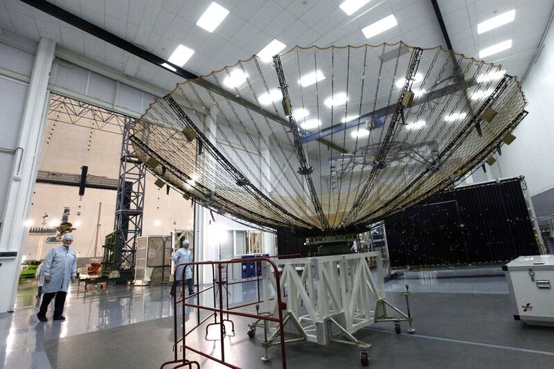 Employees walk behind an antenna of the Luch space satellite. Ilya Naymushin / Reuters