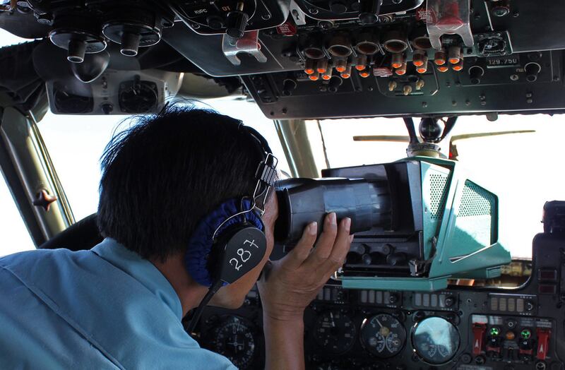 A military personnel member scans for wreckage from the Malaysian Airlines Boeing 777 along the Vietnamese seaboard on a Vietnamese Air Force aircraft.  Thanh Nien Newspaper / AFP Photo / March 8

