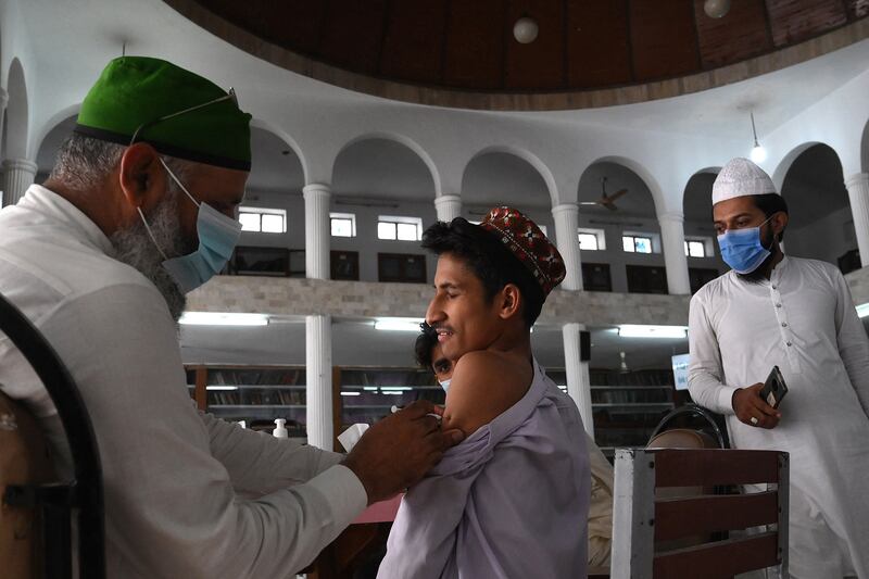 A health worker inoculates a student with a dose of the CanSino Biologics vaccine at Jamia Naeemia seminary in Lahore, Pakistan.