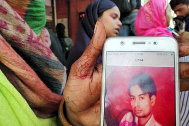 Relatives show pictures of family members who became victims of the deadly violence in Delhi. Taniya Dutta for The National