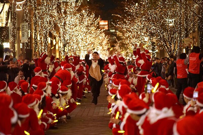 People dressed in Santa Claus costumes attend a parade under winter illuminations at Marunouchi business district in Tokyo.   AFP