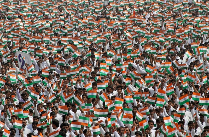 Employees of Sahara Group wave miniature national flags before singing India's national anthem in the northern Indian city of Lucknow May 6, 2013. More than 100,000 employees of the company attempted to create a new world record by singing the country's national anthem together at the same place in identical uniforms, said organisers.   REUTERS/Pawan Kumar (INDIA - Tags: BUSINESS SOCIETY) - GM1E9561PKB01