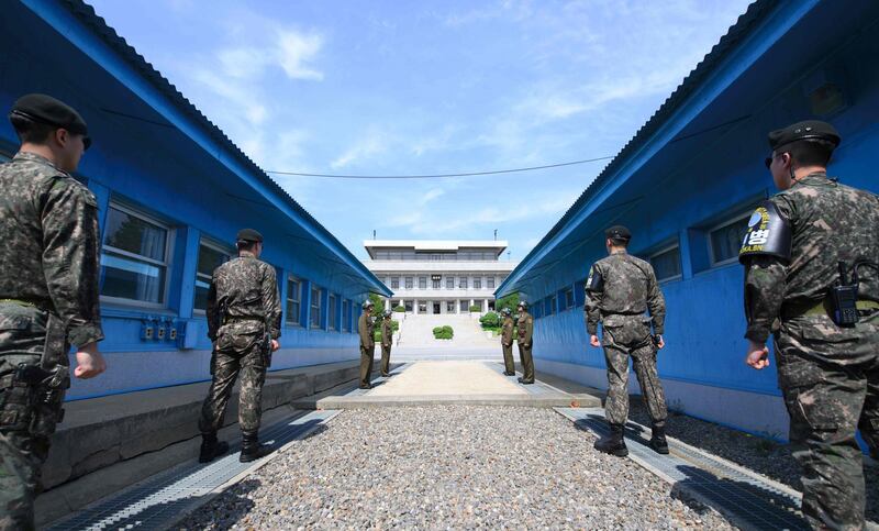 South Korean soldiers (front) and North Korean soldiers (rear) stand guard before the military demarcation line on the each side of the truce village of Panmunjom in the Demilitarized zone (DMZ) dividing the two Koreas on April 26, 2018 ahead of the inter-Korea summit. Korea Summit Press Pool / AFP Photo