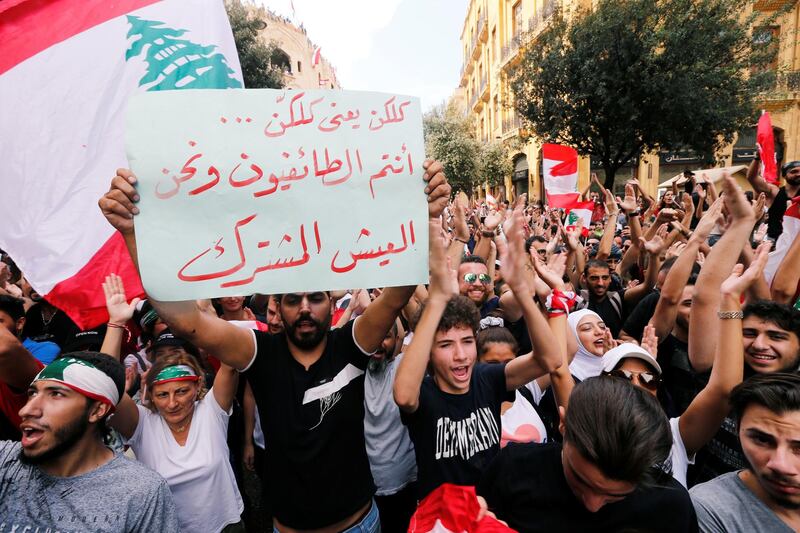 A demonstrator holds a banner during an anti-government protest in downtown Beirut, Lebanon October 20, 2019. The banner reads ''You are the sectarians and we are the co-existentialists''. REUTERS/Mohamed Azakir