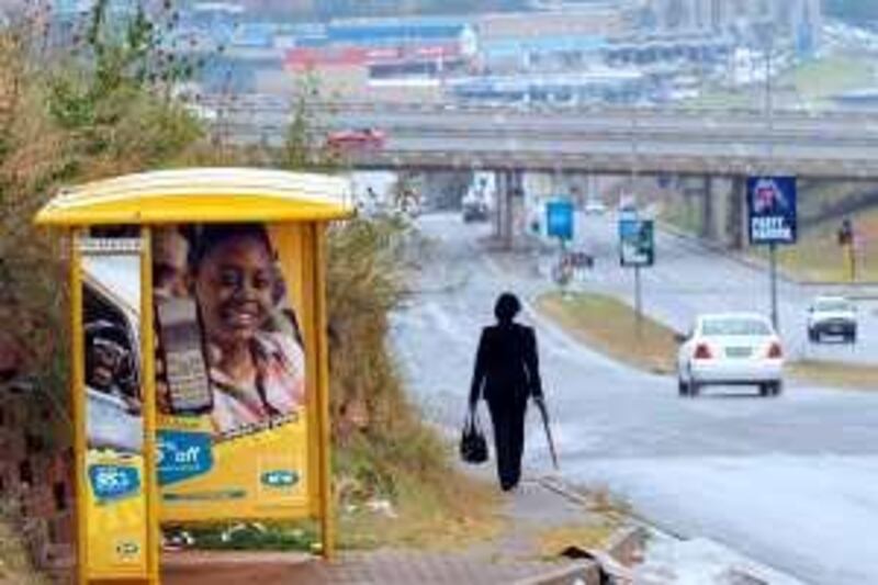 A woman walks past a bus shelter advertising South Africa's MTN Group in Johannesburg, May 27, 2008. MTN Group and India's Reliance Communications may swap shares or take big stakes in a new company as regulatory hurdles and both firms' global ambitions seem to rule out a $66 billion emerging markets telecoms merger.  REUTERS/Mike Hutchings (SOUTH AFRICA)