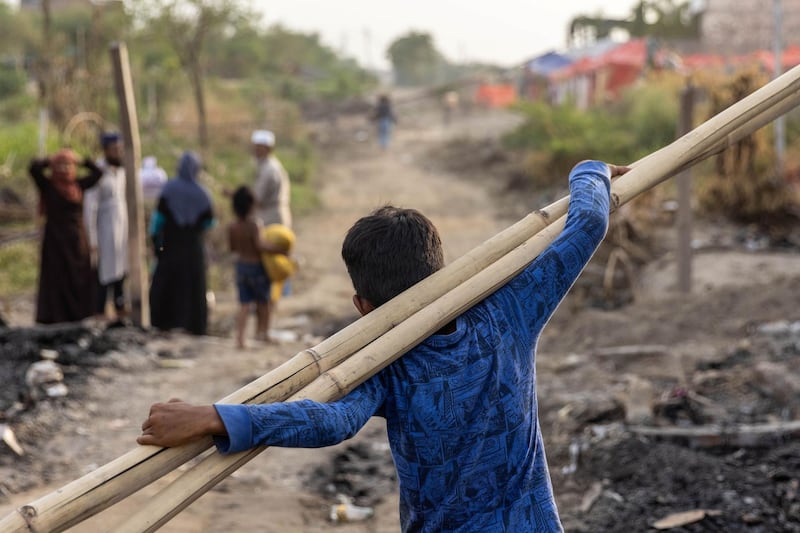 A Rohingya refugee carries bamboo sticks to a temporary shelter after a fire destroyed a Rohingya refugee camp on Saturday night, in New Delhi, India, June 14, 2021. REUTERS/Danish Siddiqui