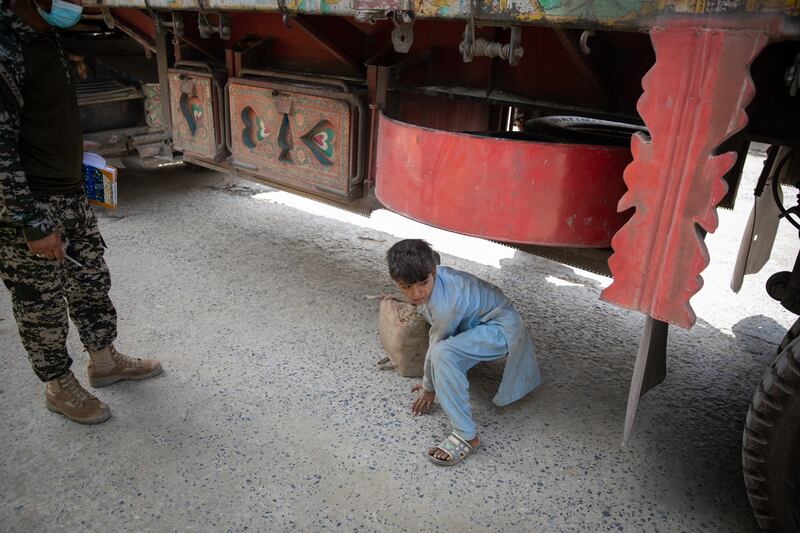 A border guard from Pakistan catches a child hiding in the undercarriage of a lorry in his attempt to smuggle into Pakistan.