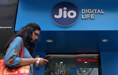 FILE PHOTO: A woman checks her mobile phone as she walks past a mobile store of Reliance Industries' Jio telecoms unit, in Mumbai, India, July 11, 2017. REUTERS/Shailesh Andrade/File photo