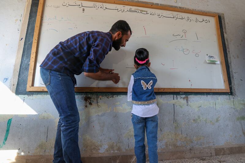A teacher helps a child on the first day of school in Syria's northwestern Idlib province. Unicef has said millions of Arab children continue to live in 'digital poverty'.