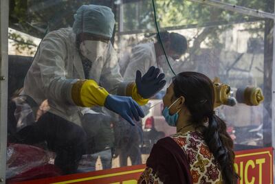 NEW DELHI, INDIA - APRIL 30: An Indian health official inside a COVID-19 mobile testing van uses a nasal swab to collect a sample from a woman, as India remains under an unprecedented extended lockdown over the highly contagious coronavirus (COVID-19) on April 30, 2020 in New Delhi, India. India eased the lockdown restrictions by allowing neighbourhood shops and standalone shops in areas that havent been marked coronavirus hotspots to sell goods on the condition of 50 per cent staff strength and following other protective guidelines like wearing masks and maintaining social distance. With a total number of over 33,000 positive cases, the death toll due to coronavirus in India has reached 1079 as the country reels under a nationwide lockdown that was imposed on March 25 by the government. (Photo by Yawar Nazir/Getty Images)