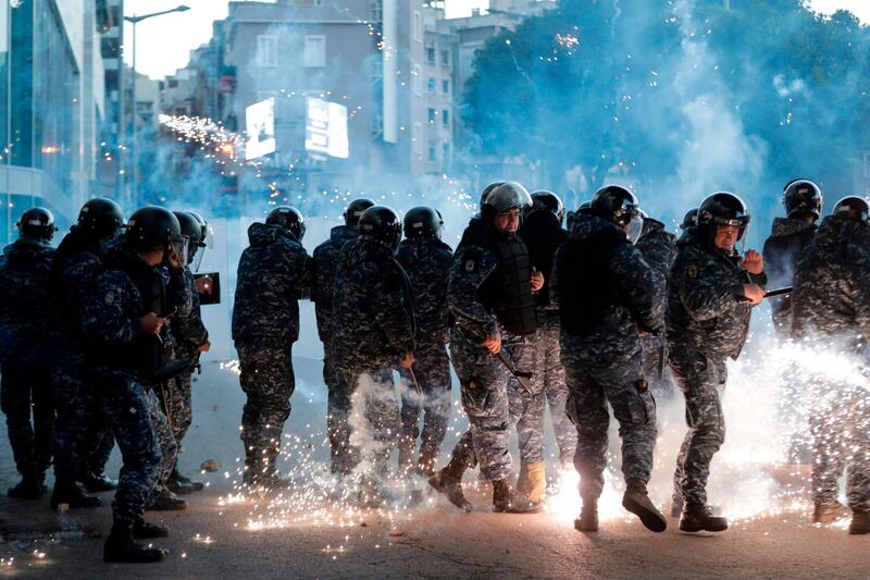 Lebanese riot police react to fireworks thrown by supporters of Lebanon's Shiite Hezbollah and Amal groups during clashes on December 14, 2019 in central Beirut.  AFP