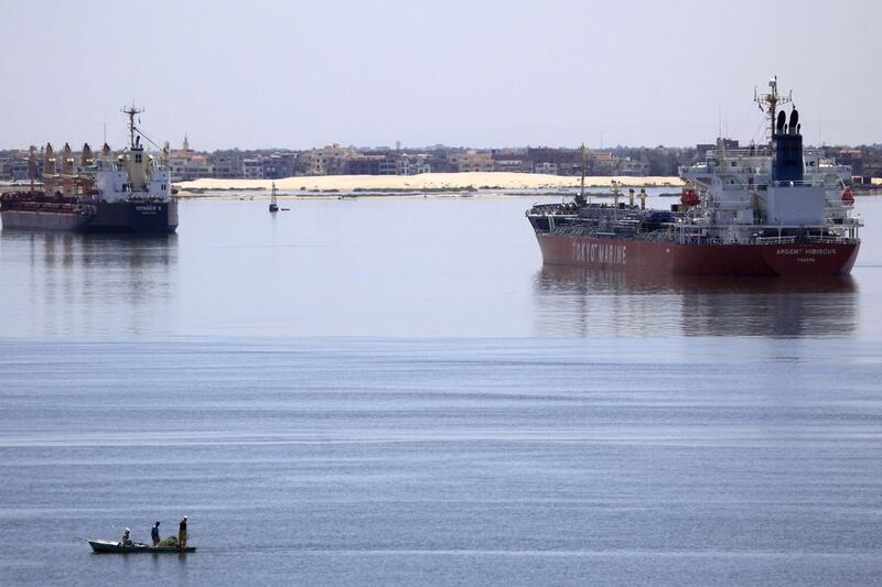 A fisherman travels on a boat with his family in front of a Voyager K bulk carrier ship, left, and a Tokyo Marine tanker, right, in the Suez Canal. Amr Abdallah Dalsh / Reuters