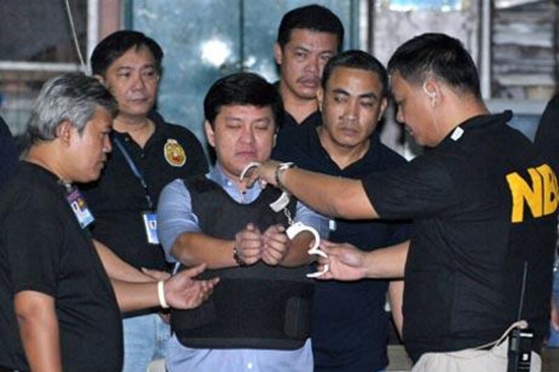 Andal Ampatuan Jr  is handcuffed by an agent before the latest hearing in his murder trial in Manila.