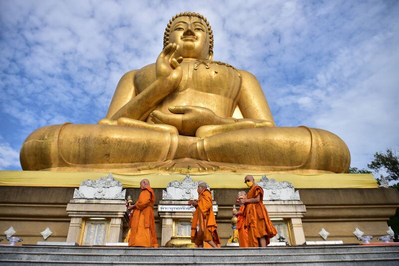 Buddhist monks walk around a giant statue of Buddha statue as they perform religious rites in Narathiwat, Thailand. AFP