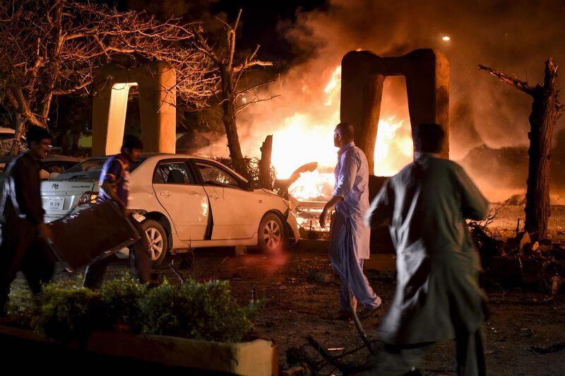 Volunteers search for victims next to burning vehicles at the site of an explosion in Quetta. AFP